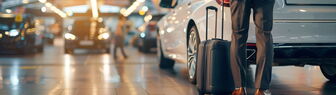 Business Traveler Selecting Rental Car at Airport Terminal with Suitcase Von doraclub
